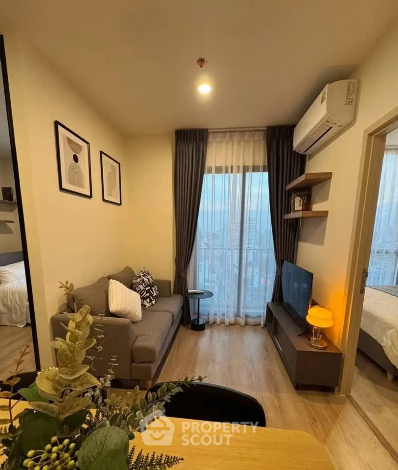 Modern living room with cozy decor and city view, featuring a stylish sofa and wall-mounted TV.