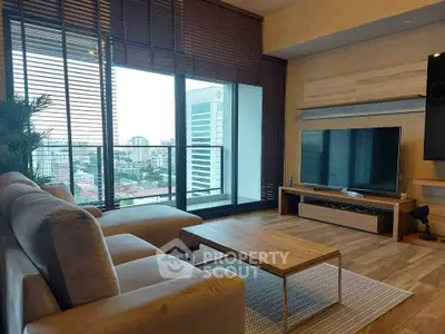 Modern living room with large windows and city view, featuring a cozy sofa and sleek entertainment unit.