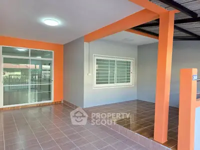 Spacious covered patio with vibrant orange accents and tiled flooring, perfect for outdoor relaxation.