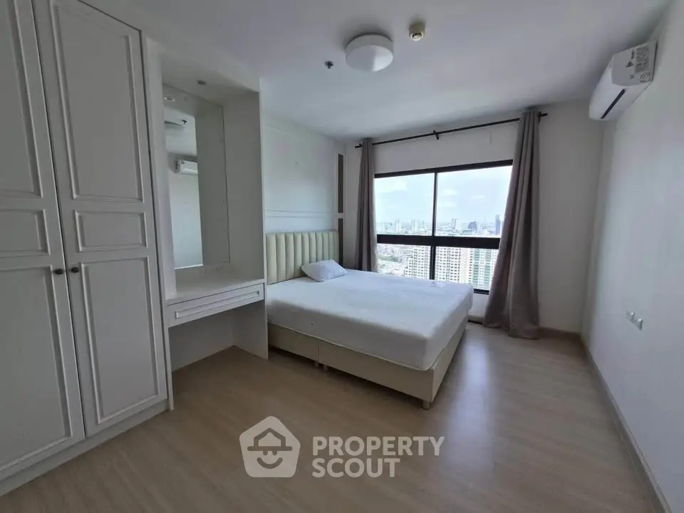Spacious bedroom with city view, featuring a large window, built-in wardrobe, and modern furnishings.