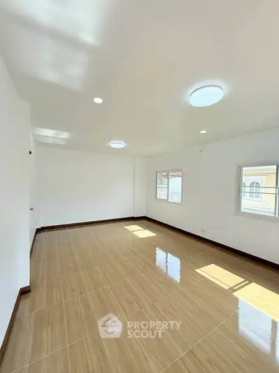 Spacious and bright empty room with large windows and polished wooden floors, perfect for customization.