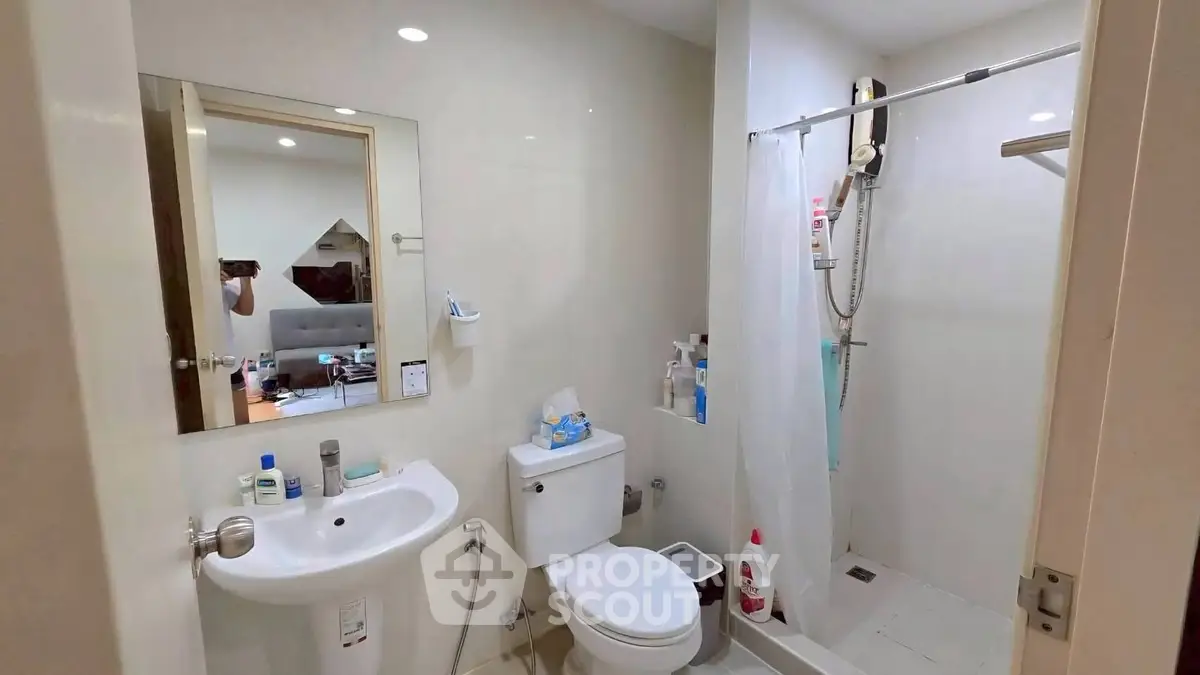 Modern bathroom with shower, toilet, and sink in a sleek design.