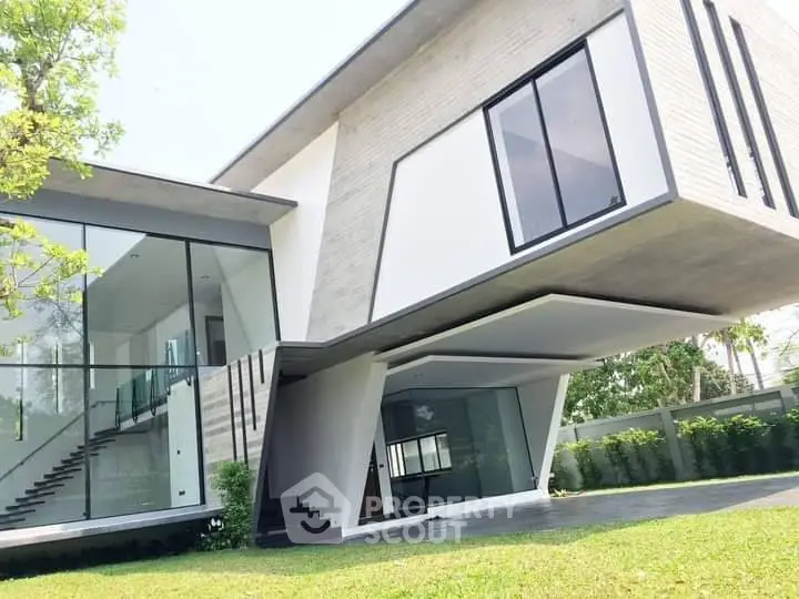 Modern architectural marvel with sleek lines and expansive glass windows in a lush green setting.