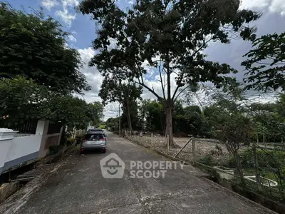 Scenic residential street with lush trees and parked car, ideal for tranquil living.