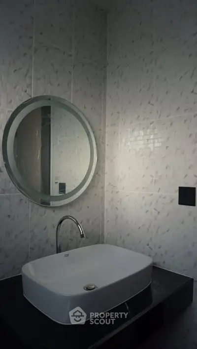 Modern bathroom with stylish round mirror and sleek sink design.