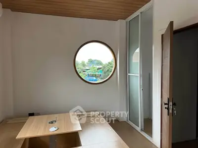 Modern minimalist room with circular window and wooden flooring