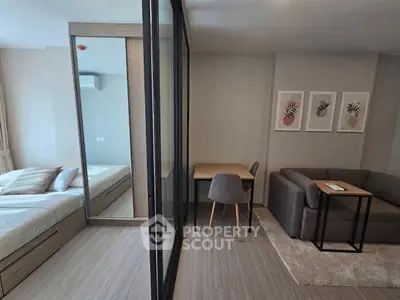 Modern studio apartment with cozy living area and stylish bedroom separated by glass partition.