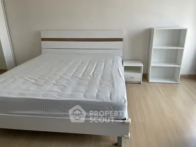 Minimalist bedroom with white bed frame and wooden flooring, ideal for modern living.