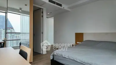 Modern bedroom with city view, featuring sleek furniture and large windows for natural light.