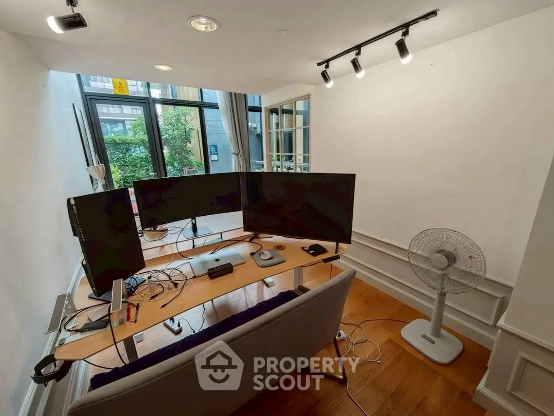 Modern home office with dual monitors and garden view, perfect for productivity.