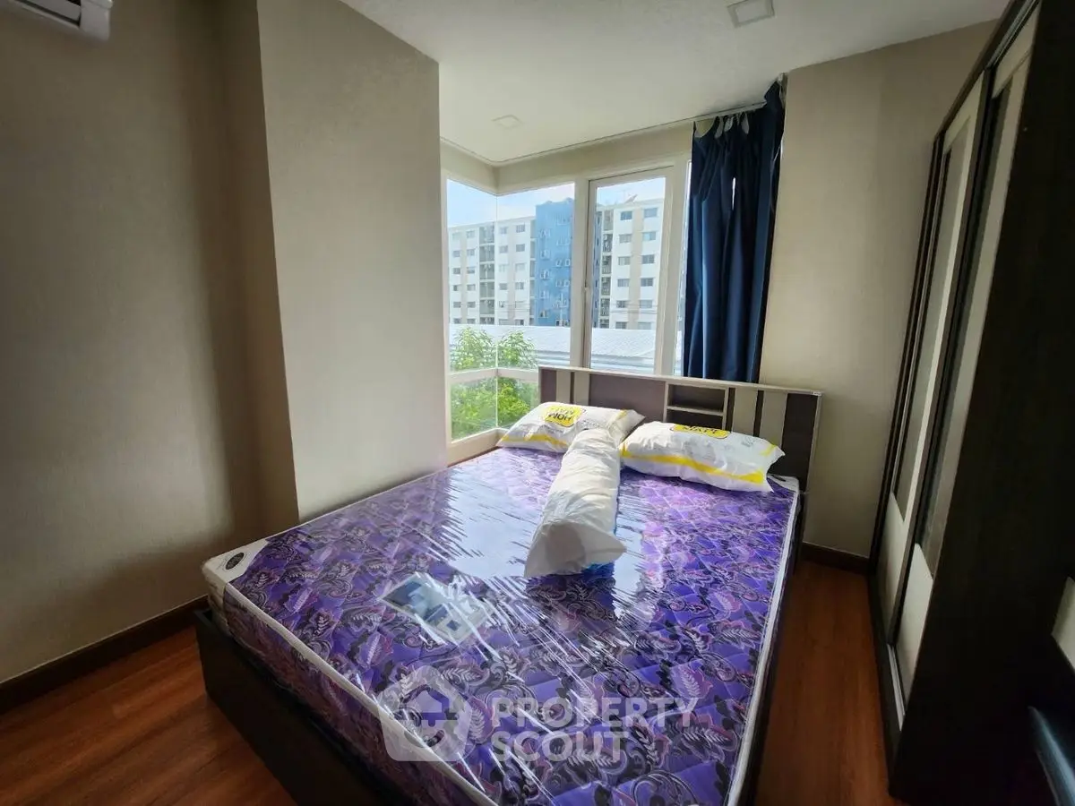 Bright bedroom with large windows and modern decor in urban apartment.