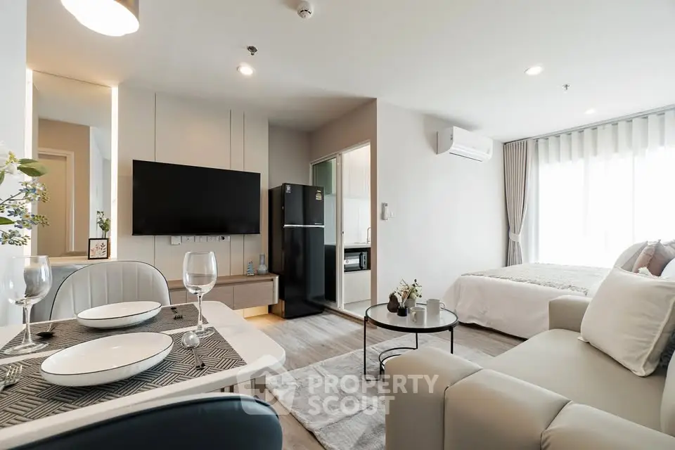 Modern open-plan living room with dining area and cozy bedroom in a stylish apartment.