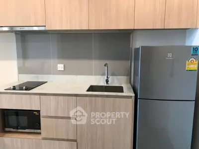 Modern kitchen with sleek cabinetry, built-in appliances, and compact fridge in a stylish apartment.