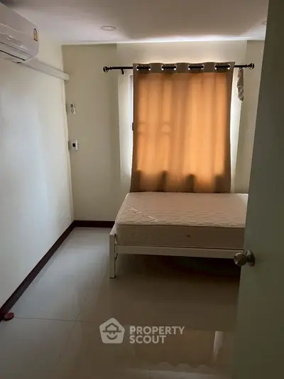Cozy bedroom with natural light and minimalist design, featuring a bed and air conditioning.