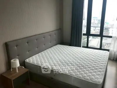 Spacious bedroom with large window offering city views, featuring a comfortable bed and modern decor.
