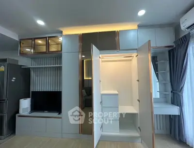 Modern living room with built-in storage and sleek design, featuring open wardrobe and entertainment unit.