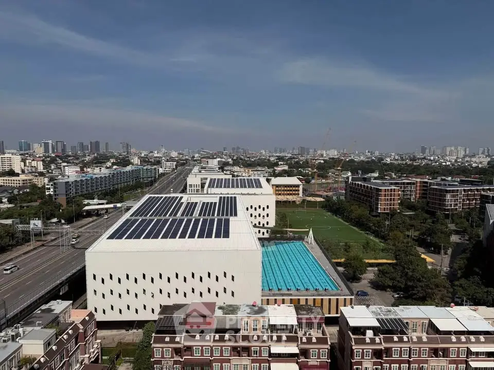 Aerial view of modern buildings with solar panels and a swimming pool in an urban setting.