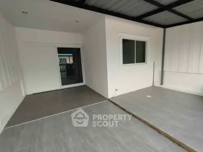 Spacious covered patio with tiled flooring and sliding glass door entry, perfect for outdoor relaxation.
