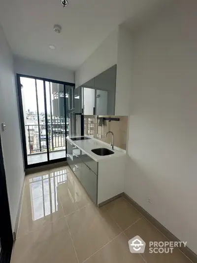 Modern kitchen with sleek cabinetry and balcony view in urban apartment