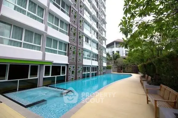 Modern apartment building with a sleek swimming pool and lush greenery.