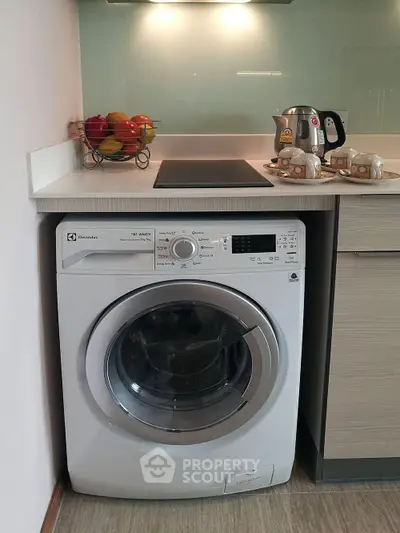 Modern kitchen with built-in washing machine and sleek countertop appliances.