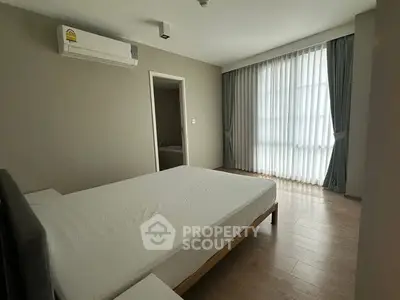 Spacious bedroom with large window and modern air conditioning unit, perfect for comfort and relaxation.