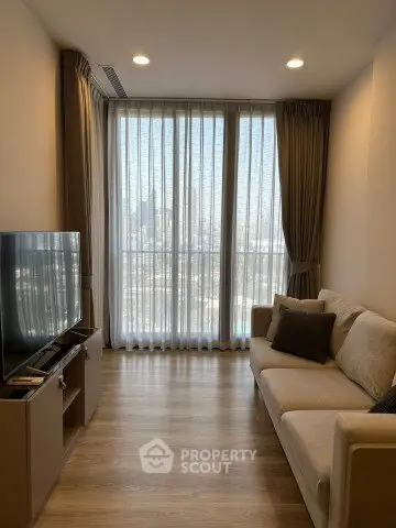 Modern living room with large window and city view, featuring a cozy sofa and flat-screen TV.