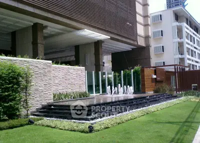 Luxurious building entrance with modern water feature and lush landscaping