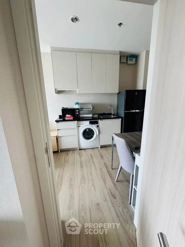 Compact modern kitchen with washing machine and sleek appliances in a cozy apartment setting.