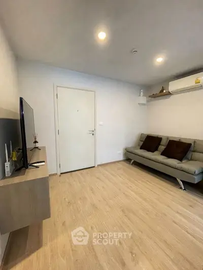 Modern living room with sleek design, featuring a cozy sofa and wall-mounted TV, perfect for relaxation.