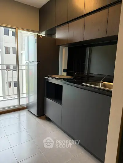 Modern kitchen with sleek cabinets and large fridge in a high-rise apartment.