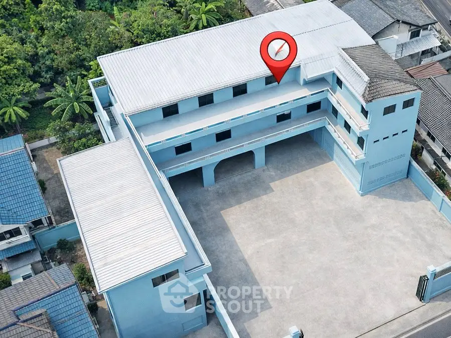 Aerial view of a blue multi-story building with spacious courtyard, ideal for commercial use.