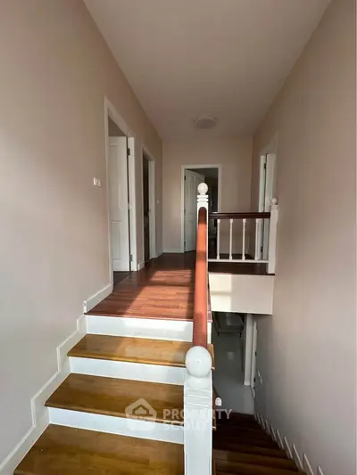 Spacious hallway with wooden staircase and natural light in modern home