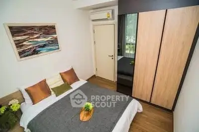Cozy bedroom with modern decor and ample natural light, featuring a stylish wardrobe and air conditioning.