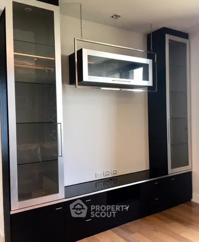 Modern living room with sleek black cabinetry and glass display shelves.