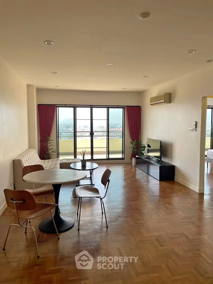 Spacious living room with parquet flooring and large windows offering a stunning view.