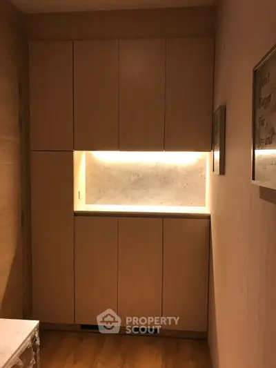 Elegant built-in wooden storage with marble countertop and ambient lighting