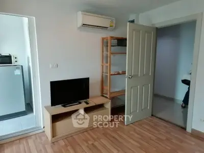 Cozy living room with wooden flooring, TV stand, and air conditioning in modern apartment.