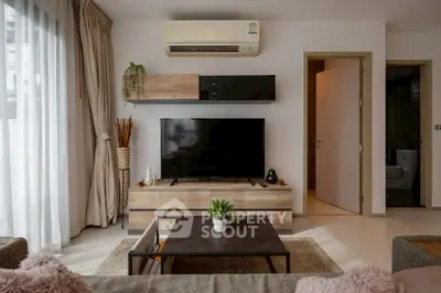 Modern living room with stylish decor, flat-screen TV, and natural light.