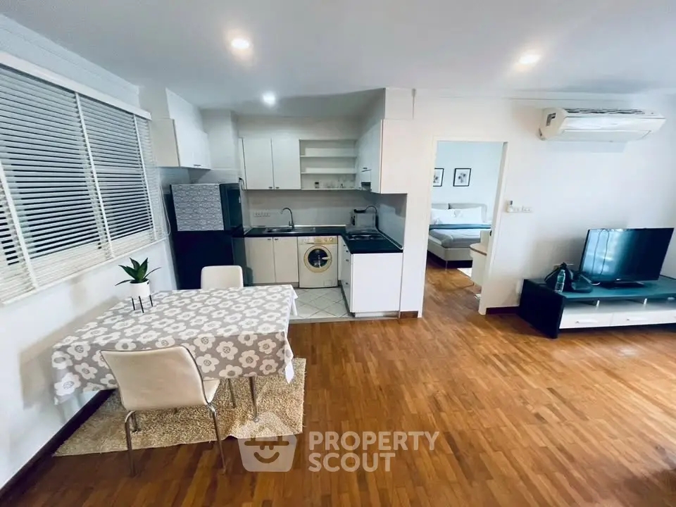 Charming open-layout living room with kitchen, featuring wooden floors and modern appliances, perfect for cozy living.