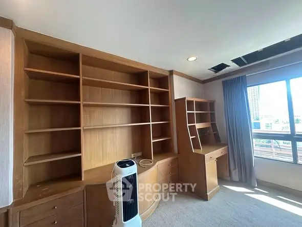 Spacious study room with built-in wooden shelves and large window view