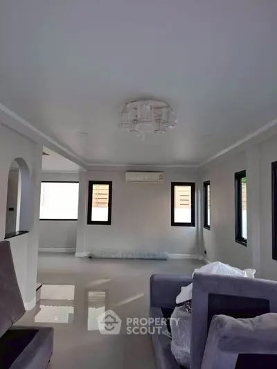 Spacious modern living room with sleek design and natural light, featuring plush seating and elegant ceiling fixture.