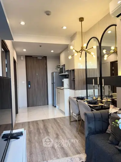 Modern open-plan living room with stylish kitchen and elegant dining area, featuring contemporary lighting and decor.