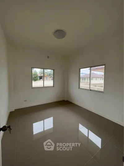Spacious empty room with large windows and glossy tiled floor, perfect for customization.