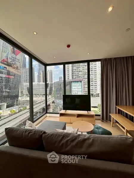 Modern living room with city view, large windows, and stylish furniture in urban apartment.
