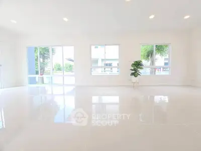 Spacious and bright empty living room with large windows and glossy floors.