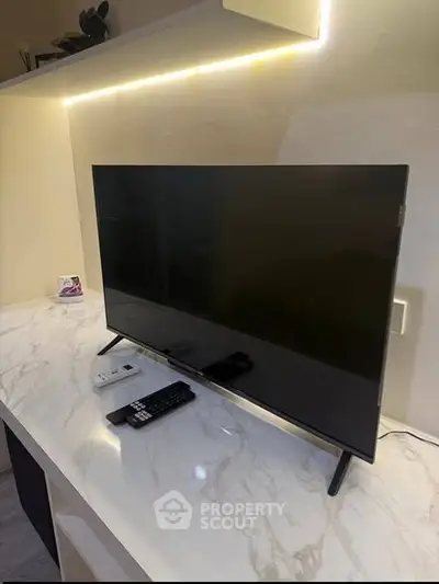 Modern living room with sleek TV on marble countertop and ambient lighting.