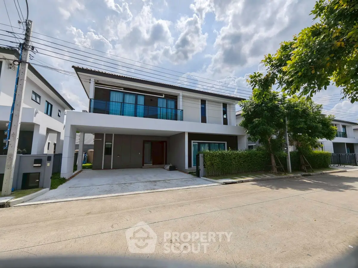 Modern two-story house with large windows and driveway in a suburban neighborhood.