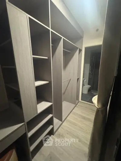 Spacious walk-in closet with modern shelving and adjacent bathroom view.