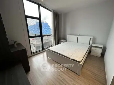 Modern bedroom with large window and city view, featuring sleek furniture and minimalist design.